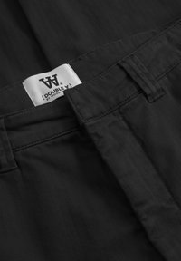 Zwarte broeken in een visgraatpatroon met een soepele textuur, voorzien van een label met "DOUBLE A" van WOOD WOOD op de tailleband.