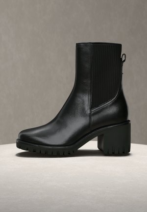 Schwarzer Leder-Stiefelette mit glatter Oberfläche, rechteckiger Zehenpartie, strukturierten elastischen Seitenteilen und einem klobigen, profilierten Absatz.