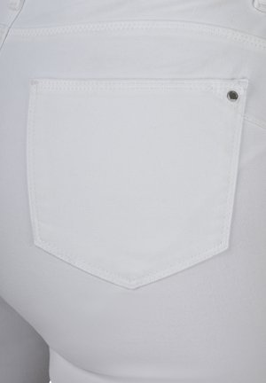 Weiße Denim-Jeans mit einer einzigen hinteren Tasche in geschwungener, hexagonaler Form und dezenten Steppnähten, die eine glatte Textur zeigen.