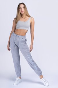 Grey cropped tank top and matching sweatpants with elastic cuffs. Sweatpants feature a white logo on one side. White sneakers complete the outfit.