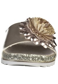 Platt sandal med metallisk taupe-överdela, stor beige blomdetalj och glittrig silverplattform. Vit gummibas med texturerat grepp.