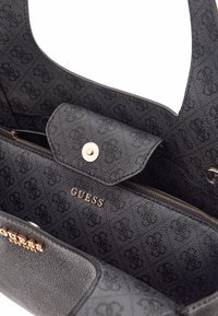 Borsa nera in tessuto testurizzato, con scomparto con zip e pattina magnetica. Logo "GUESS" in argento impresso sul davanti.