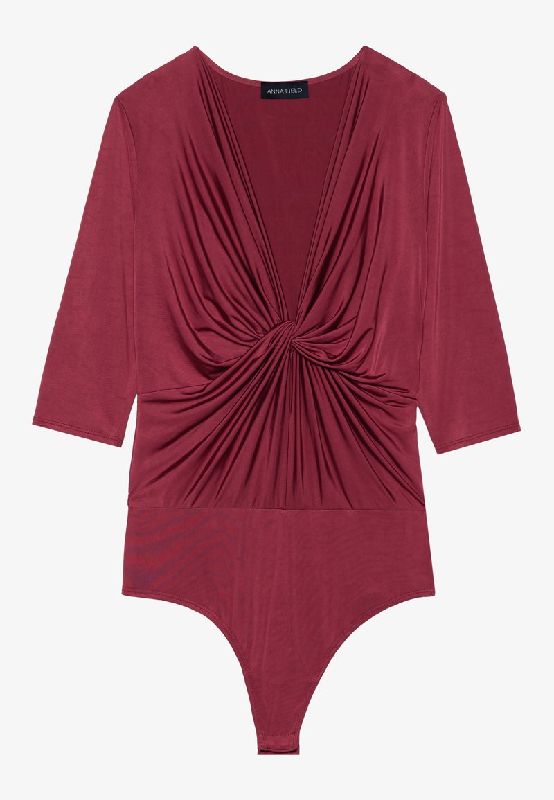 Body bordeaux con maniche lunghe, caratterizzato da un profondo scollo a V e un dettaglio drappeggiato davanti, realizzato in un morbido tessuto elastico.