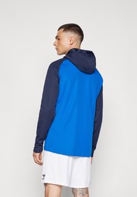 Hooded sweatshirt featuring a blue body and navy sleeves, made of soft fabric with a smooth texture, designed with a relaxed fit.