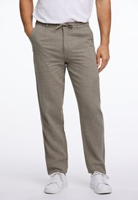 Pantalones de color gris claro, texturizados, con cintura elástica y cordón, bolsillos laterales y diseño de pierna recta, combinados con zapatillas blancas.