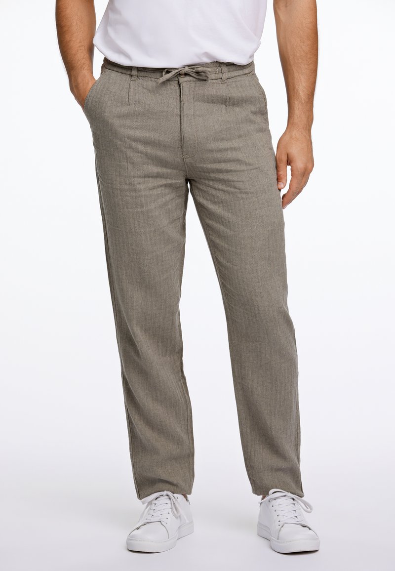 Pantalones de color gris claro, texturizados, con cintura elástica y cordón, bolsillos laterales y diseño de pierna recta, combinados con zapatillas blancas.