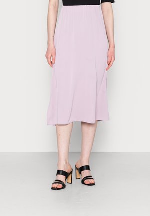 Saia midi rosa claro com cintura elástica e tecido esvoaçante. Combinada com mules pretas de salto alto com duas tiras frontais.