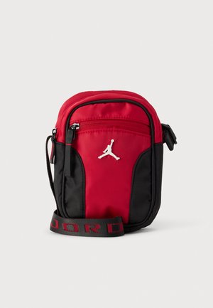 Sac bandoulière Jordan rouge et noir avec un logo Jumpman blanc, une poche avant zippée et une bandoulière siglée.