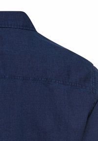 Granatowa koszula z klasycznym kołnierzykiem, teksturowaną tkaniną i przeszyciami na plecach. Bez widocznych wzorów i ozdób.