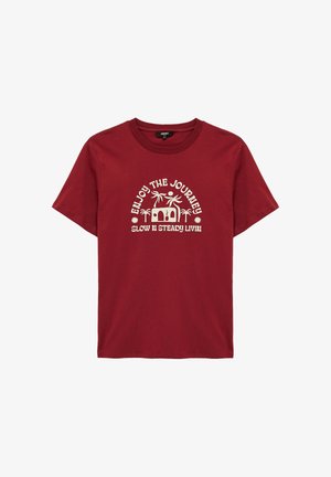 Camiseta de algodón roja con un gráfico blanco que muestra palmeras, una figura y el texto "Disfruta el viaje" y "Viviendo despacio y constante."