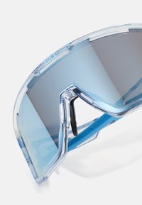 Ochelari de soare futuristici cu o ramă transparentă de culoare albastră și lentile cu un gradient. Design curbat și pernițe negre de nas ajustabile.