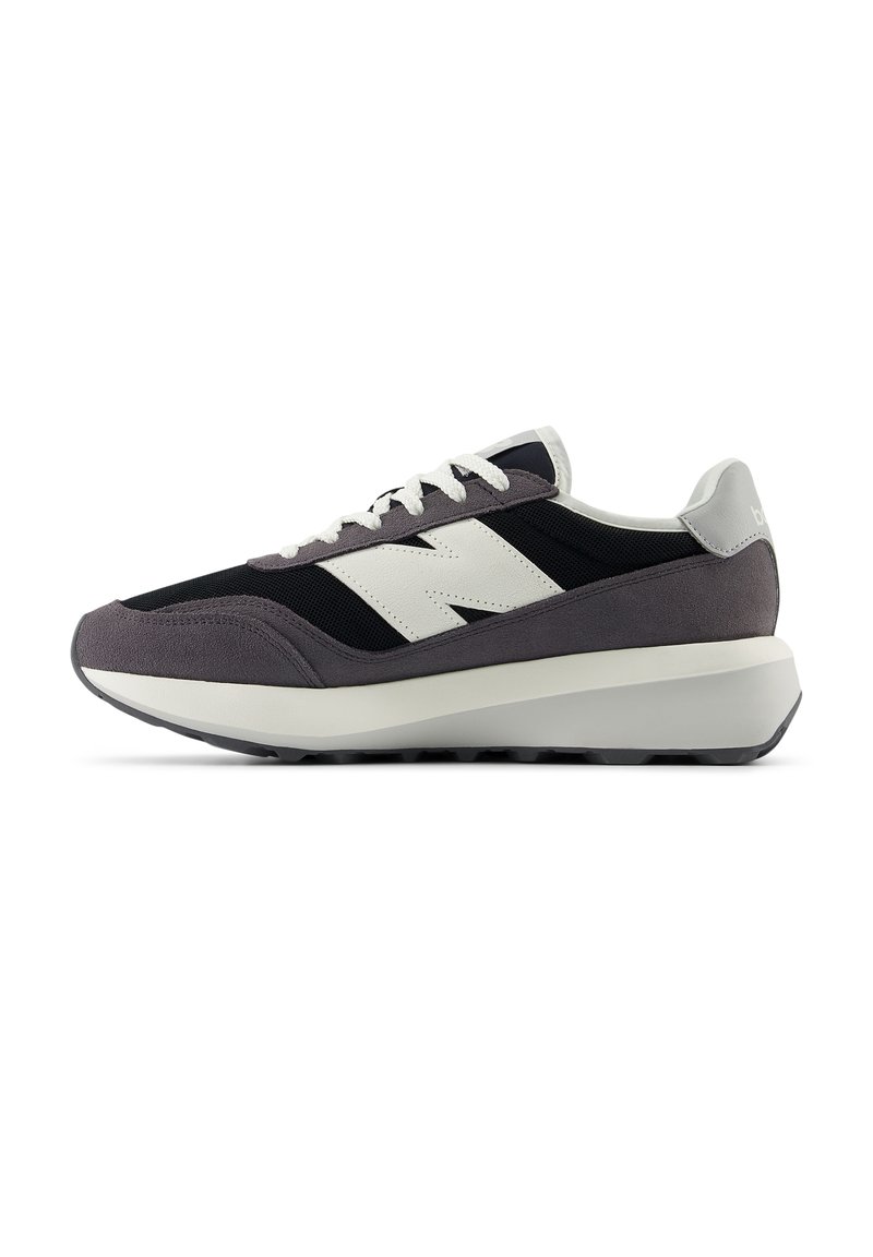 Sneaker mit schwarzem Mesh-Obermaterial, grauen Wildledereinsätzen, einer dicken weißen Mittelsohle und weißen Schnürsenkeln. Mit einem auffälligen weißen Markenlogo.