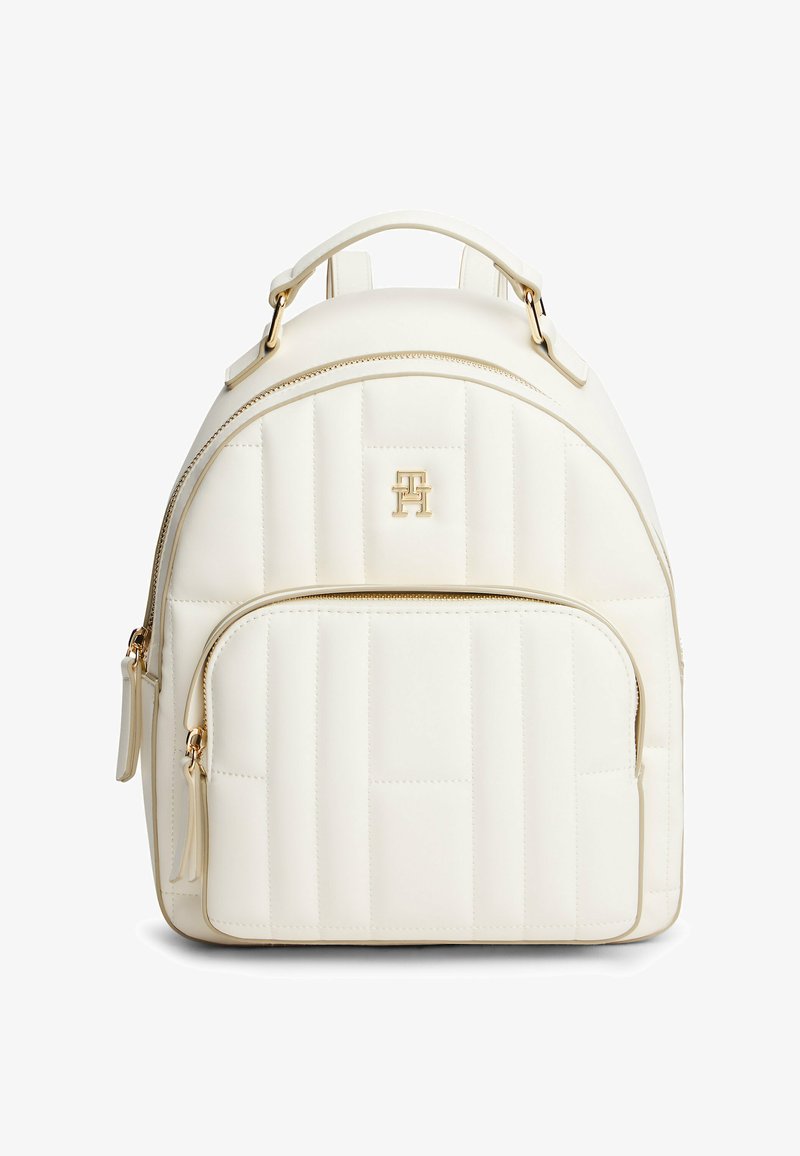 Zaino bianco trapuntato realizzato in materiale simile alla pelle, con forma arrotondata, hardware dorato e tasca anteriore con zip. Logo decorativo sul fronte.