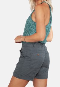 Szare bawełniane szorty z podwiniętym dołem i tylnymi kieszeniami, z luźnym pasem w talii. Cielisty top na ramiączkach w wzory dopełnia całość.