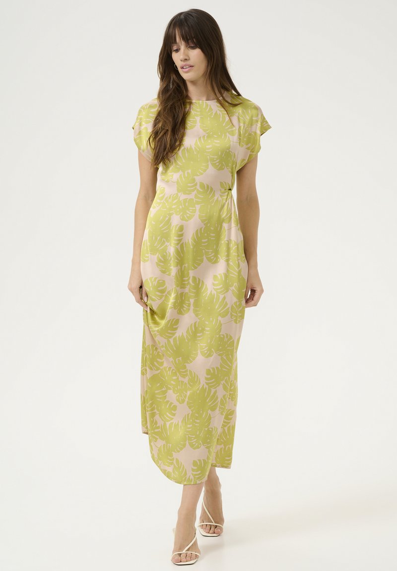 Maxi šaty z jemného růžového materiálu s zeleným tropickým vzorem listů. Mají krátké rukávy, volný střih a kapsy. Minimalistický design.