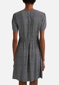Schwarz-weißes Blumendruckkleid mit kurzen Puffärmeln, elastischem Bund und ausgestelltem Rock. Weicher Stoff mit subtiler Textur, knielang.