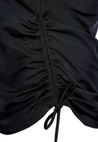 Zwarte top van gladde stof, met gatherdetails aan één kant en een strik aan de onderkant voor een verstelbare pasvorm.
