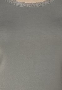 Šedý tílko s jemným žebrovaným vzorem a krajkovým lemem kolem výstřihu. Tkanina vypadá měkce a je mírně elastická.