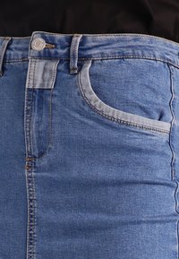 Jeans in denim blu dal design aderente, con vita standard, passanti per cintura, una tasca visibile e dettagli di cucitura a contrasto.