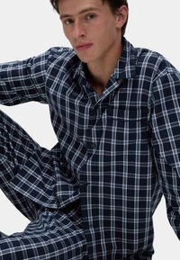 Conjunto de pijama de cuadros marinos hecho de una tela suave, que incluye una camisa de botones de manga corta con bolsillo y pantalones a juego.