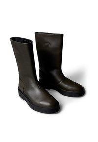 Botas de cuero verdes hasta la rodilla con punta redonda y suela gruesa de goma negra. Presentan costuras mínimas y una textura lisa.