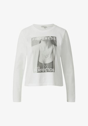 T-shirt long en coton blanc avec une impression graphique d'un col portant des colliers et le texte "PROGRÈS plutôt que PERFECTION."