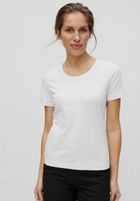 Witte t-shirt met korte mouwen en een ronde halslijn, gemaakt van een gladde stof. Het heeft een comfortabele pasvorm en wordt gecombineerd met zwarte broek.