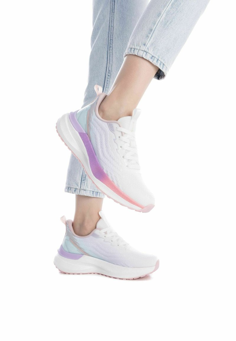 Zapatillas atléticas ligeras de color blanco con acentos en púrpura y rosa pastel, que presentan un diseño de punto texturizado y una suela acolchada.