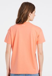 Korte mouwen, koralen t-shirt van zachte katoen. Heeft een ronde halslijn en een klein "protest" logo op de bovenrug.