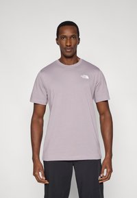 Ανοιχτό μωβ βαμβακερό μπλουζάκι με κοντά μανίκια και στρογγυλή λαιμόκοψη. Φέρει ένα μικρό λευκό λογότυπο στην αριστερή πλευρά του στήθους.