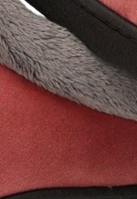 Zapatilla roja con un suave forro de piel gris. El material superior es liso con un acabado mate, mientras que la suela es de un negro contrastante.