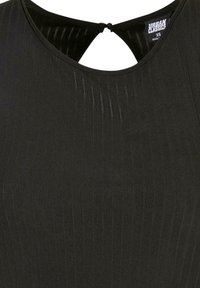 Top negro de tela acanalada con escote en forma de ojo de cerradura y pequeño cierre de botón con lazo en la parte trasera, etiqueta de talla XS visible.