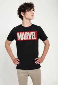 Černé bavlněné tričko s výrazným, červeně orámovaným grafickým nápisem "MARVEL" na hrudi. Krátké rukávy a design s kulatým výstřihem.