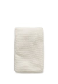 Couverture pliée en tissu côtelé blanc et doux avec une texture rayée subtile sur fond blanc.