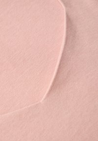 Hellrosa Textil mit einer weichen, glatten Textur, das ein dezentes, geschwungenes Muster aufweist, das Dimension verleiht. Nahaufnahme des Materials.