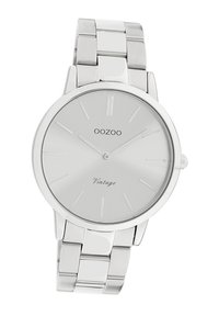 Silver stainless steel watch with a minimalist design, featuring a smooth, reflective round face and plain hour markers.
