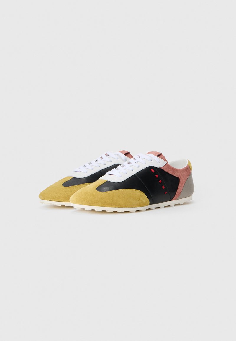Farverige sneakers med gul ruskind, sorte læderdetaljer samt pink og grå elementer. Udstyret med hvide snørebånd og en struktureret sål.