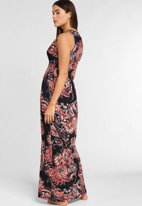 Vestido maxi en negro con vibrantes patrones florales y de paisley. Diseño sin mangas con un corsé ajustado y una falda fluida. Tela suave y ligera.
