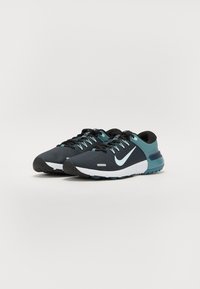 Sorte og teal atletiske sko med en tekstureret overdel, hvid swoosh-logo, runde snørebånd og en polstret sål til støtte.