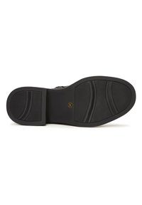 Talpa de pantof neagră cu prindere texturată, caracterizată prin linii curbe și o margine ridicată. Logo circular de aur în centrul său. Material din cauciuc durabil.