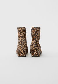 Läbi kõrge kand mittesüsteemse leopardimustri ankle boots, nähtavad tagant lihtsalt heledal taustal.