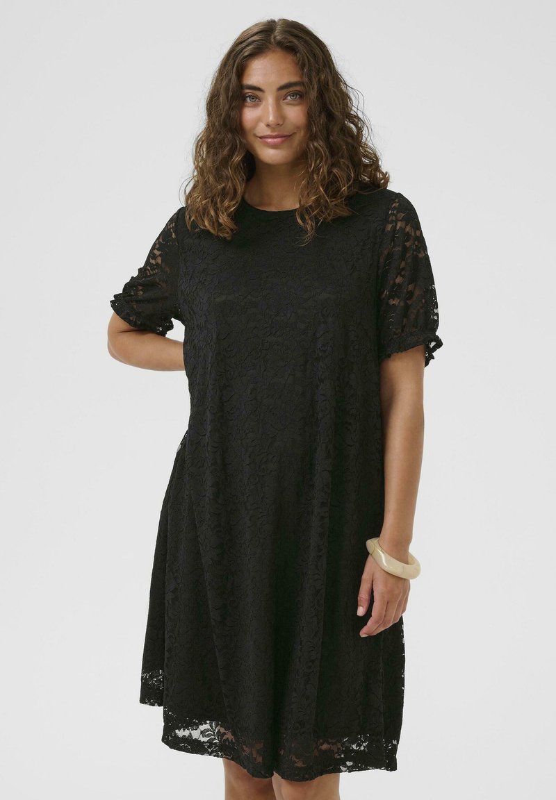 Fekete csipkeruha rövid ujjakkal, laza szabással, kerek nyakkivágással és virágmintával. Középhosszú szegélydíszítéssel és áttetsző anyaggal kiemelve.