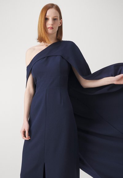 Abito da sera blu navy, con scollo off-the-shoulder e un dettagliato drappeggio fluente, caratterizzato da un corpetto aderente e uno spacco frontale per facilitare il movimento.