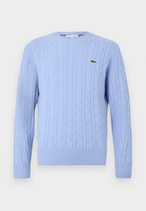 Light blue cable-knit sweater with a round neckline, ribbed cuffs, and hem. Features a small green logo on the left chest.