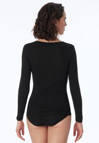 Schwarzes Langarmoberteil aus weichem Material, mit einem runden Ausschnitt und einer taillierten Silhouette, in einem glatten, nahtlosen Design.