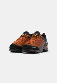 Wandelschoenen met een ademende oranje mesh bovenkant, zwarte rubberen zool en oranje accenten. Beschikt over een gestructureerd oppervlak en een duurzame constructie.