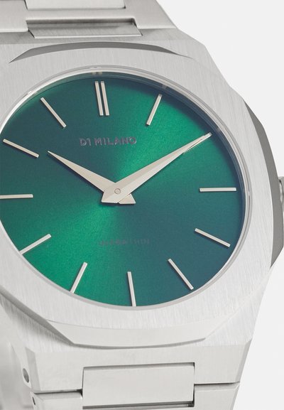 Stříbrné nerezové ocelové hodinky s oktagonálním pouzdrem, které mají tmavozelený přechodový ciferník, minimalistické indexy a tenké zlaté ručičky.