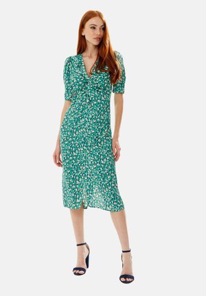Green dress with short puff sleeves, gathered neckline, and a knee-length hem. It features a colorful abstract pattern and a side slit.