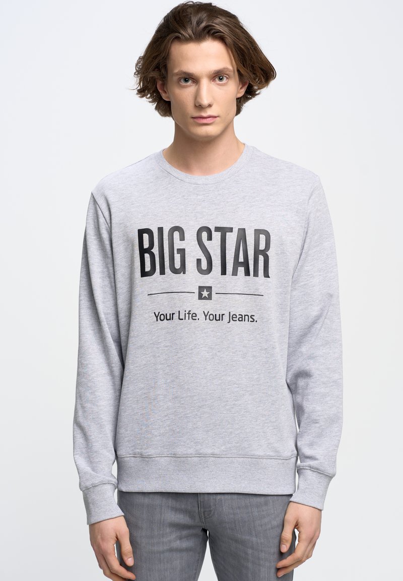 Siv sweatshirt z dolgimi rokavi, okrogel izrez in črn natisnjen tekst: "BIG STAR" in "Tvoje življenje. Tvoje kavbojke." Brez vzorcev ali akcentov.