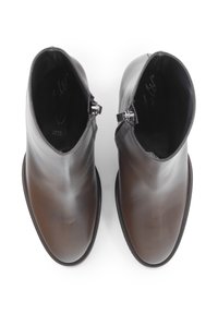 Stivali alla caviglia in pelle marrone con finitura liscia, chiusura con cerniera, punta rotonda e dettagli di cucitura sottili.